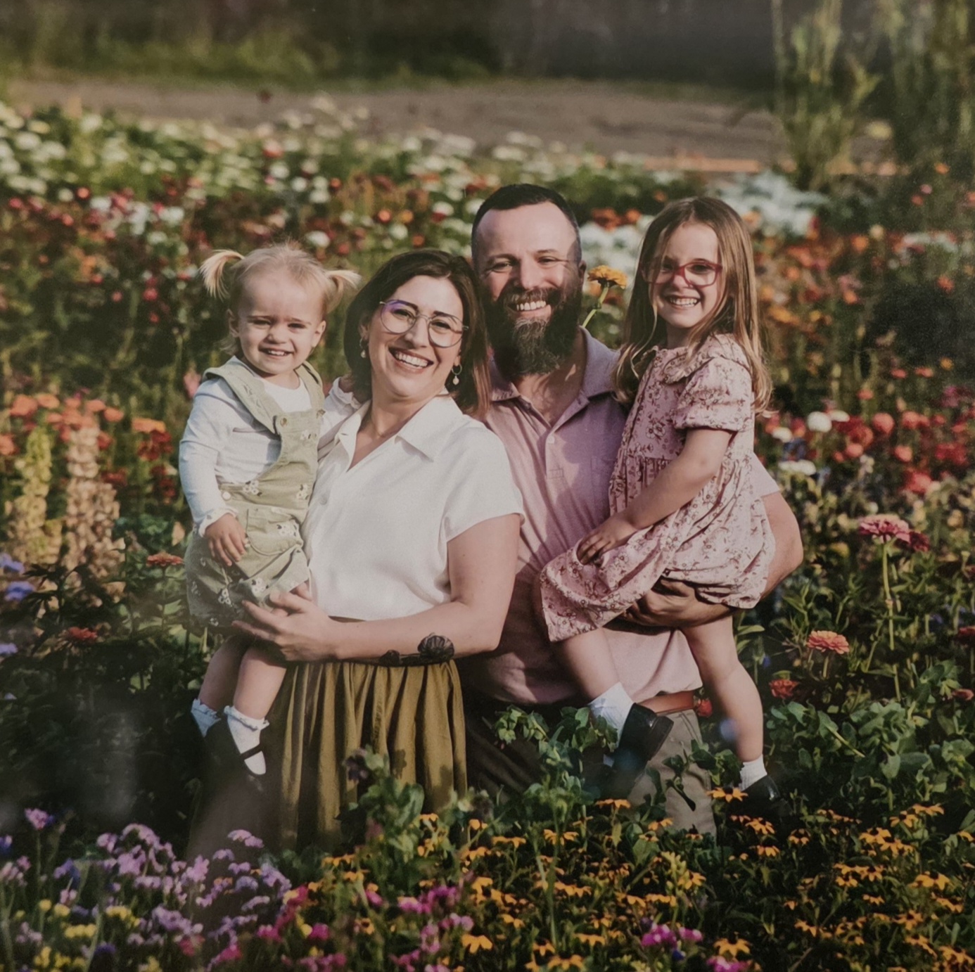 A smiling family with Jade and Michael, as well as their two children Olivia and Phoebe in a field of flowers